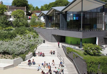 students sitting on steps outside a glass fronted building 