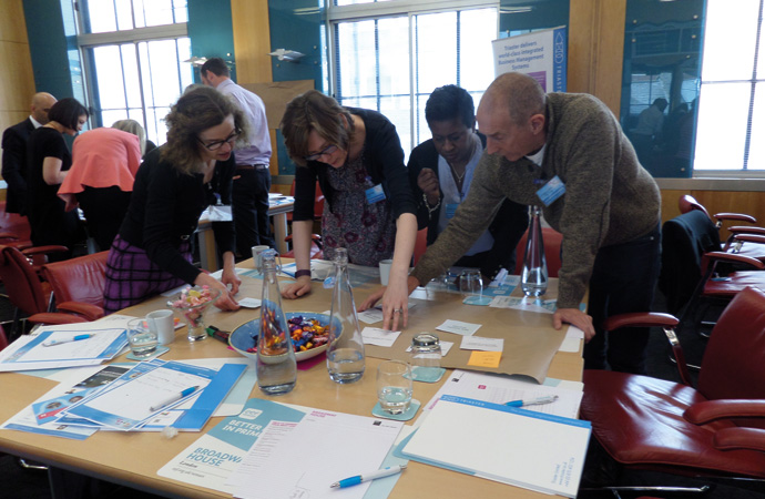 4 people bending over a table working together 