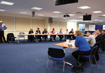 many business people at two desks watching a presentation