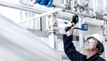 A man in PPE looking up at a collection of pipes