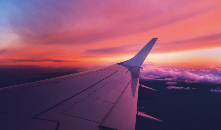 An airplane wing flying during sunset 