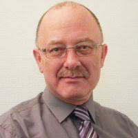 A headshot of a man with a moustache and glasses 