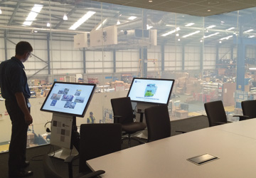 two TV screens with a factory behind them
