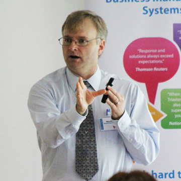 a man in a white shirt and tie presenting animatedly 