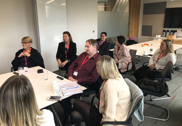 people in business dress sitting down around a table having a discussion