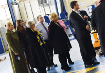 people in business dress standing on the factory floor