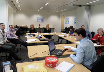 people in business dress sitting around a large desk 