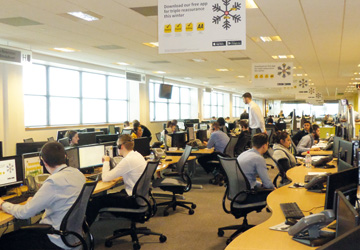 an office with yellow desks and people sitting at them
