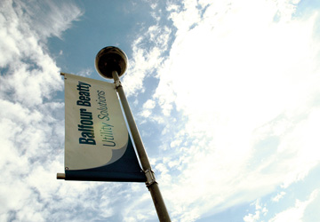 a balfour beatty flag with a blue cloudy sky behind it 