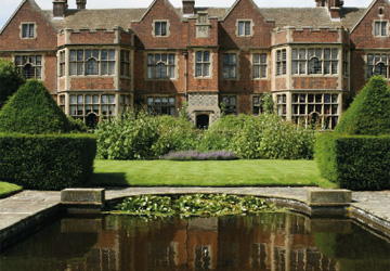 a large stately home with a lawn and pond in front of it