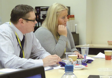 two people in business dress sat at a desk 