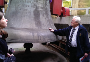 a man leaning on a large bell 