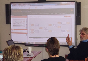 a man pointing at a process map projected on screen 