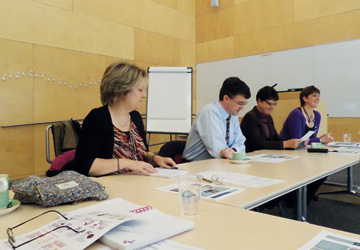 people in business dress sitting around at a desk  