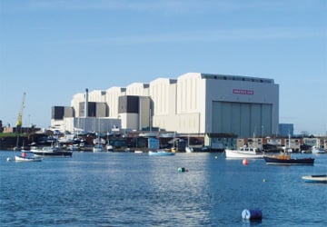 a large white building next to the sea with boats into it