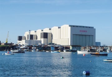 a large white building next to the sea with boats into it 