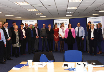 a line of people in business dress smiling in front of a blue screen 