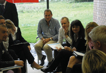 business people sitting on chairs and leaning forwards to talk 