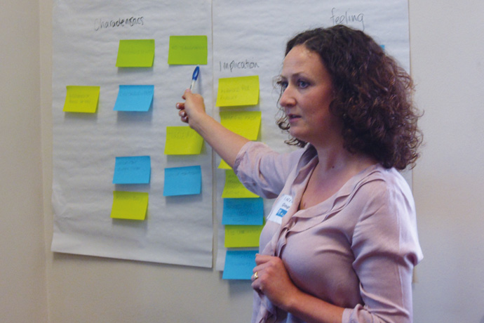 a woman pointing at a sheet of paper with post-it notes on them 