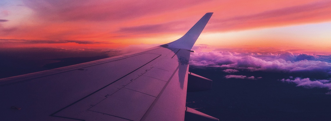 An aeroplane wing flying at sunset