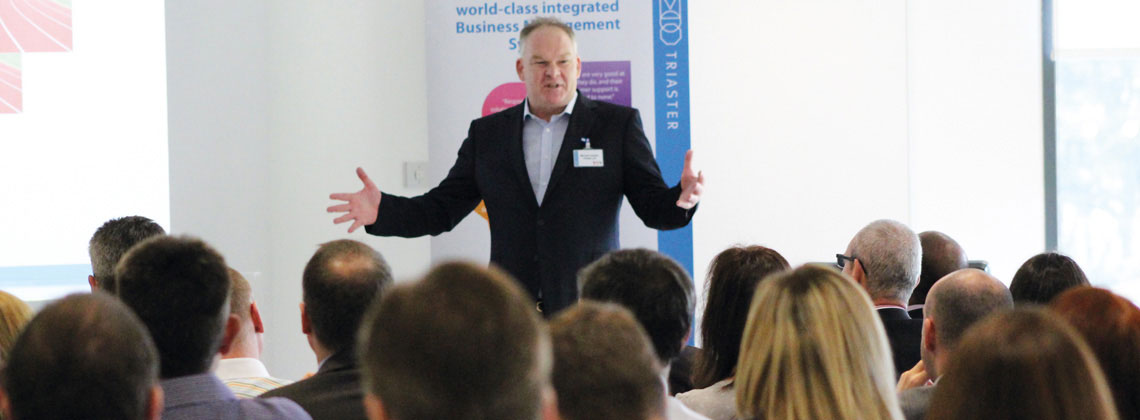 a man in a suit presenting to an audience 